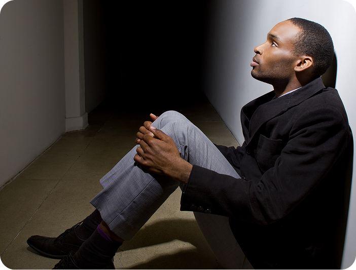 Man sitting alone in a dark hallway looking toward light — symbolizing reflection, decision, and the turning point offered by 2Inspire Publications.